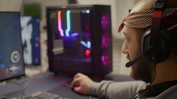 Competitive cyber pro gamer streaming with microphone, playing first person shooter game during virtual tournament. Player using professional RGB system desktop in gaming home studio late at night video