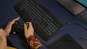 Closeup of wireless joystick and RGB keyboard, pro gamer playing online games on powerful computer. Player using professional equipment during gaming online competition video