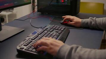 Closeup of player hands using RGB keyboard in gaming home studio. Digital gamer using professional equipment for first shooter game person competition late at night in living room video