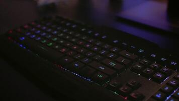 Close-up of professional keyboard with RGB lighting during online gaming tournament. Home studio of esport game player using powerful gaming PC video
