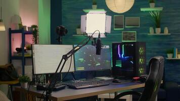 Empty streaming room with professional powerful computer, RGB keyboard and mouse, headphones and mirophone. Player talking with other players on streaming chat during online competition video