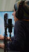 Vertical . Pro cyber woman talking at streaming professional microphone in gaming home studio with open stream chat. Gamer performing in online tournament using powerful personal computer with RGB and headset video