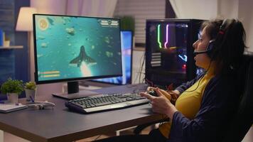 Pro player talking into microphone with other players for space shooter tournament. Gamer using wireless joystick for online championship on powerful computer late at night in gaming room video