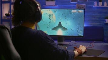 Excited pro gamer with professional headphones making winner gesture while playing space shooter games. Player streaming digital games during online competition using RGB system desktop video