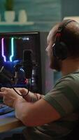 Vertical . Pro cyber streamer losing videogame tournament while wearing professional headset holding wireless controller. Defeated gamer using joystick for online competition late at night in gaming room video