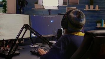 Back view of pro streamer playing game competition use professional setup with streaming chat open. Gamer sitting on gaming chair using professional headphones late at night in home studio video
