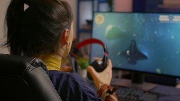 Cyber gamer playing space shooter game using RGB keyboard and professional headset during gaming tournament. Player talking with multiple players using headphones while streaming games video