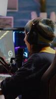 Vertical . Pro streamer checking sound on mixer putting on headset and start playing FPS game during virtual competition. Gamer using professional streaming setup, stream chat in gaming home studio video