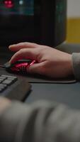 Vertical . Close up hands shot of man player typing on RGB keyboard buttons while playing online shooter game. Virtual shooter game performing in cyberspace, esports gamer esports online tournament video