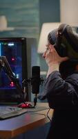 verticale . banderole en mettant sur casque de musique et début parlant dans microphone avec autre joueurs pendant en ligne Jeu professionnel concours. pro joueur séance sur jeu chaise dans diffusion Accueil studio avec rgb video