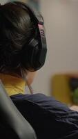 Vertical . Focused woman gamer sitting on desk, putting on headset with a mic and starts playing space shooter game. Online streaming cyber performing on powerful personal computer during gaming tournament video