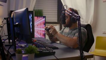 Side view of pro streamer man with headphones playing online games with streaming chat open. Cyber performing on powerful computer in gaming room home using professional console video