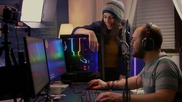 Side view of pro streamer couple performing online games using powerful computer with multiple monitors. Player playing space shooter games during e-sport online tournament in streaming studio video
