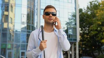 Handsome blinded man with walking stick talking on the phone video