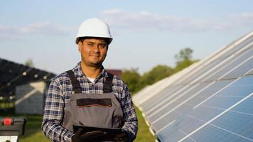 Portrait of Indian engineer with digital tablet on solar panels station. Concept of alternative and renewable energy video