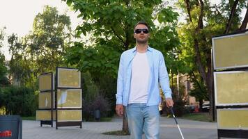 A blind man walking in city and using cane on pavement video