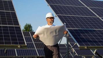 Senior 50s engineer checks technical documentation of the solar station after installation video