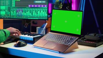 Music producer mixing and mastering songs on digital post production pc interface, green screen display. Artist adding sound effects and adjusting volume levels to produce new music. Camera A. video