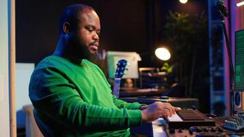 Skilled music producer creating new songs on midi controller synthesizer, working with mixing console and professional software on pc. Artist using piano and mastering acoustical tunes. Camera A. video