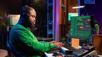Audio technician works with recording tools in his home studio, using mixing console and pre amp knobs to add sound effects on tracks. Composer editing new tunes in post production. Camera A. video