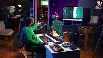 Artist composer recording a new track on his home studio microphone, editing his song with professional gear. Adjusting volume levels and adding sound effects, mix and master. Camera B. video