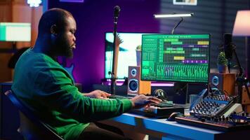 Audio composer playing piano electronic keyboard to create a new track, adjusting volume levels on old recordings. Music producer recording sounds, plays tunes on midi controller. Camera A. video