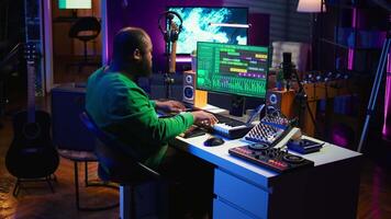 Artist playing electronic piano keyboard notes and recording audio files to use mix and master techniques, editing recordings to edit sound effects. Musician operating on synthesizer gear. Camera B. video