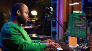 Talented artist composing new lyrics for his tracks and recording music with audio devices in his home studio. Singer composer writes melodic material by taking notes and creating rhymes or songs. Camera A. video