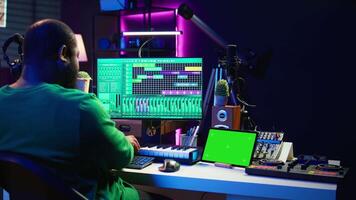 Artist producer creating new music with mix and master techniques, using a screen with copy space layout. Skilled audio engineer editing tracks in post production, digital audio software. Camera B. video