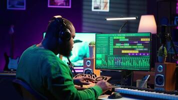 African american music producer twisting knobs on mixing console, produce tracks with sound effects. Artist composing songs in post production, operates on digital software in home studio. Camera A. video