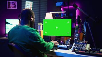 Artist plays midi controller synthesizer next to green screen layout, working on producing new music with his audio musical instruments in home studio. Musician using isolated copy space. Camera B. video