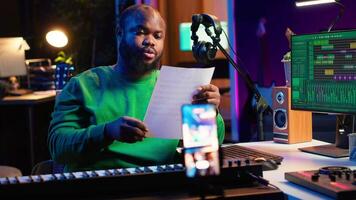 Talented composer explaining musical sheet notes during online master class recorded with smartphone in home studio. Artist musician teaching people how to read and sing accords on piano. Camera A. video