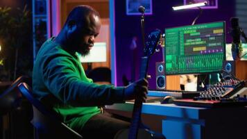 Creative songwriter singing a melody and playing guitar, signal processing technology with digital audio software. Artist producer creating music with acoustic instrument and console. Camera A. video