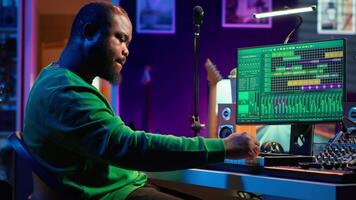 Artist playing piano electronic keyboard and recording new sounds, producing new midi controller notes in his home studio. Audio producer working with digital audio workstation software. Camera A. video
