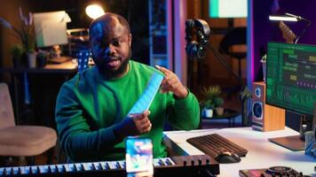 Skilled performer explaining sheet with musical notes on online tutorial, internet lessons in home studio. Producer artist teaching how to read acoustical notation, playing piano. Camera A. video