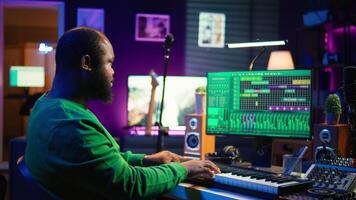 Musician playing piano keyboard and recording tracks for mix and master session, using digital software on pc to create new songs. Sound producer composing music with midi controller tool. Camera B. video