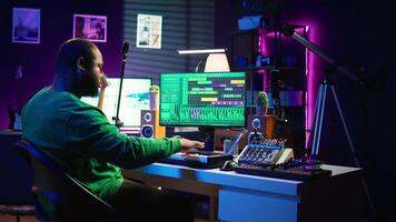 Audio composer playing piano electronic keyboard to create a new track, adjusting volume levels on old recordings. Music producer recording sounds, plays tunes on midi controller. Camera B. video