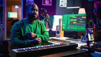 Artist songwriter hosting online master class to teach piano lessons on internet vlog, electronic keyboard notes in home studio. Young composer playing on synthesizer, recording . Camera B. video