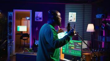 Young artist singing his new song creation on microphone gear, editing his recordings to adjust volume levels with mix and master techniques. Singer composing a melody, stereo tools. Camera B. video