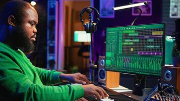 Sound engineer playing piano and mixing tunes on digital software, composing new songs and adding audio effects in post production. Artist composer creating soundtracks for music industry. Camera B. video
