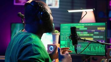 Artist producer singing a new song to record on microphone, preparing to edit music in post production. Musician expert applying mixing and mastering techniques on his audio recorded files. Camera A. video