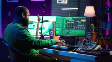 Sound engineer pressing keys of electronic synthesizer and composing new song, adjusting volume levels on pre amp knobs. Composer producing music on piano midi controller, mixing tunes. Camera A. video