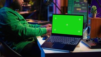 Professional artist operating on daw software in home studio, using a green screen layout next to him. Producer editing his audio recordings by applying mixing and mastering techniques. Camera A. video