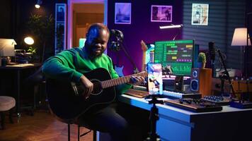 Guitarist instructor hosting guitar lessons online using a mobile phone, recording tutorial for master class. Artist musician explains acoustic instrument accords, assistance for beginners. Camera B. video