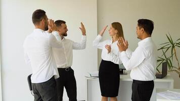 Diverse business professionals high five during a meeting in boardroom. Business team celebrating a triumph of project video