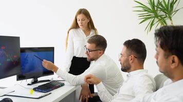 uma equipe do comerciantes análises a estoque mercado. diverso grupo do pessoas de negócio usando uma computador enquanto trabalhando juntos dentro uma moderno área de trabalho video