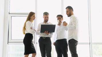 Smiling diverse businesspeople having a discussion while collaborating on a new project with laptop in an office video