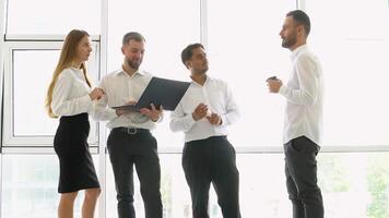 Smiling diverse businesspeople having a discussion while collaborating on a new project with laptop in an office video