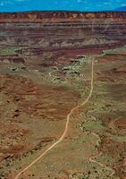 Dirt road at the bottom of the canyon among the layered geological formations of red rocks. photo