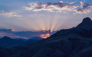 Sun rays in the clouds at sunset in the mountains of Karadag, Crimea photo